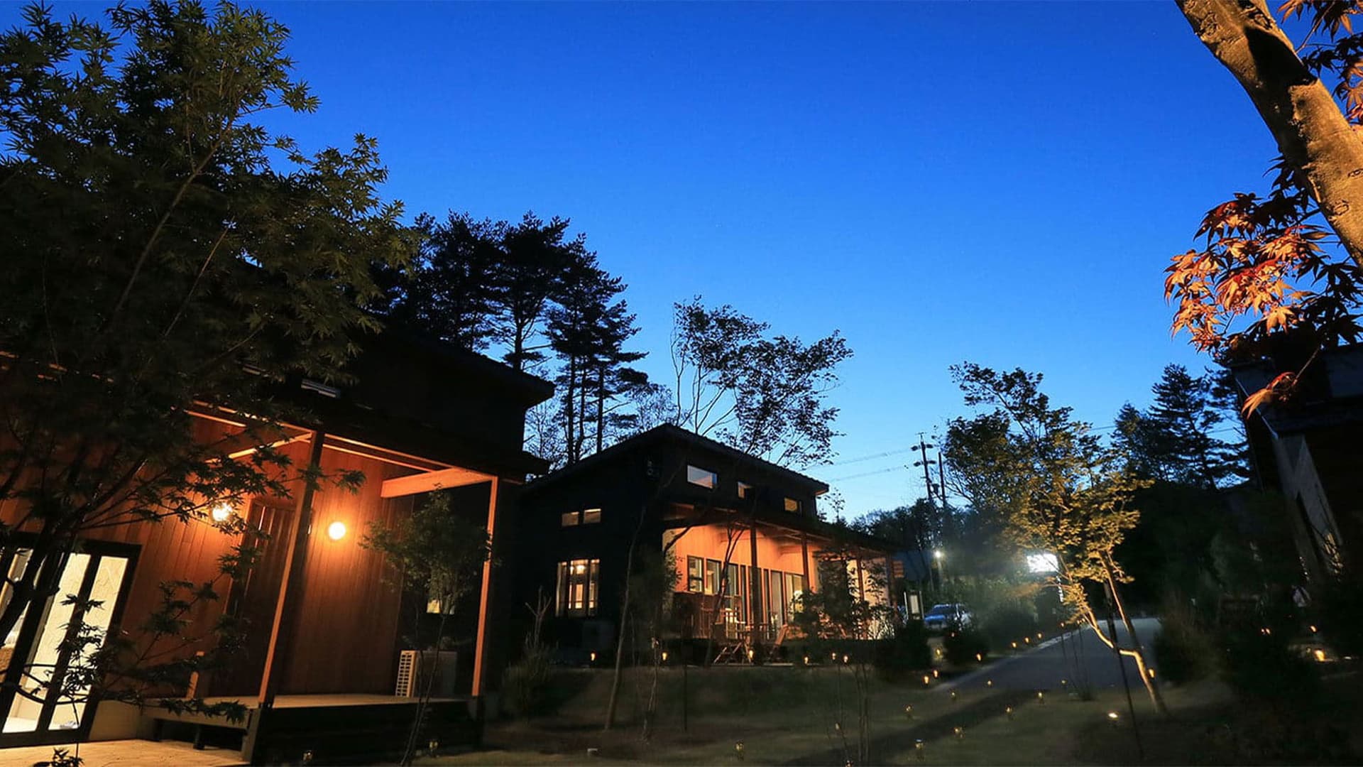 画像：夜の明かりに照らされた木造ゲストルームの外観